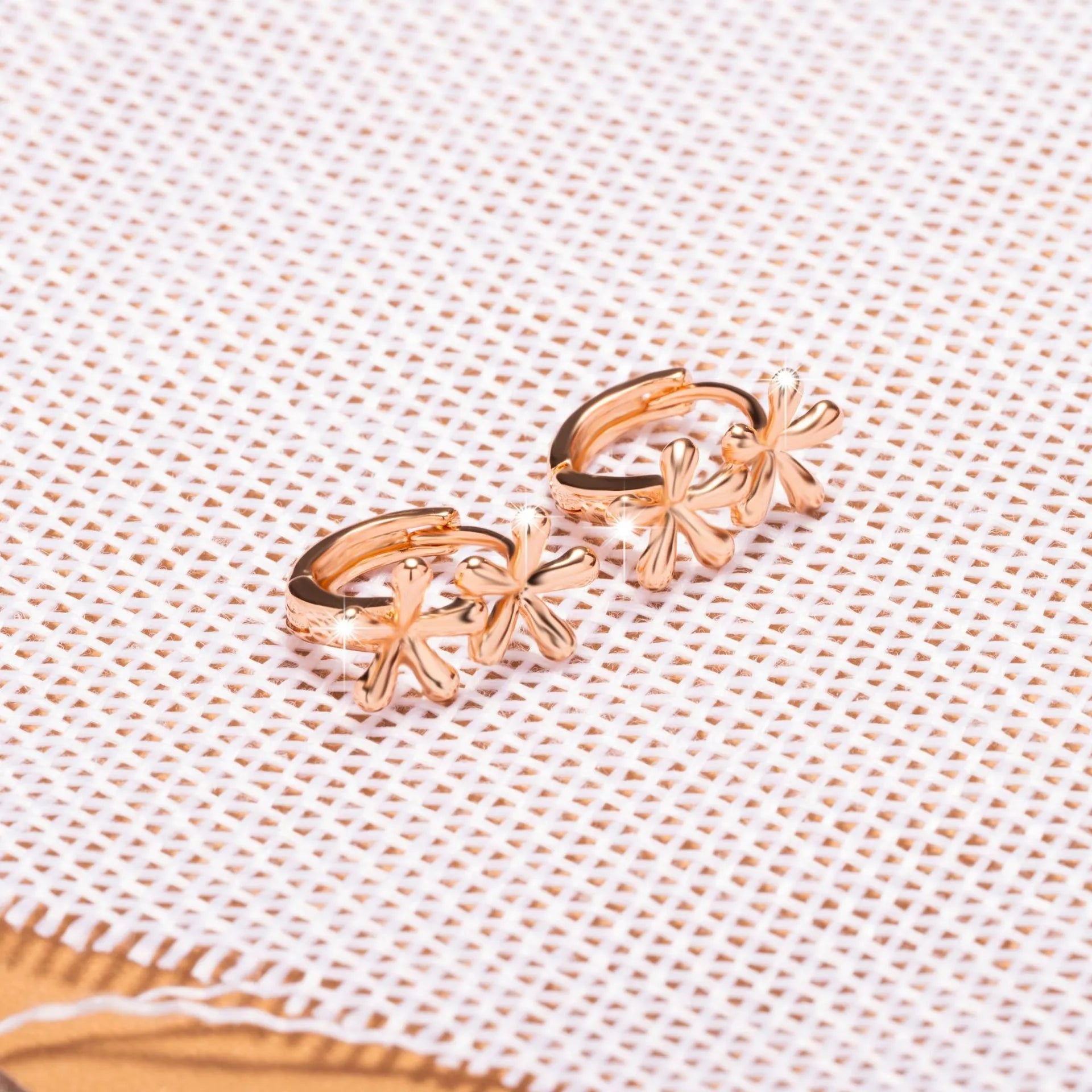 Rose gold circular earrings with a raised waterdrop floral design on a white background.