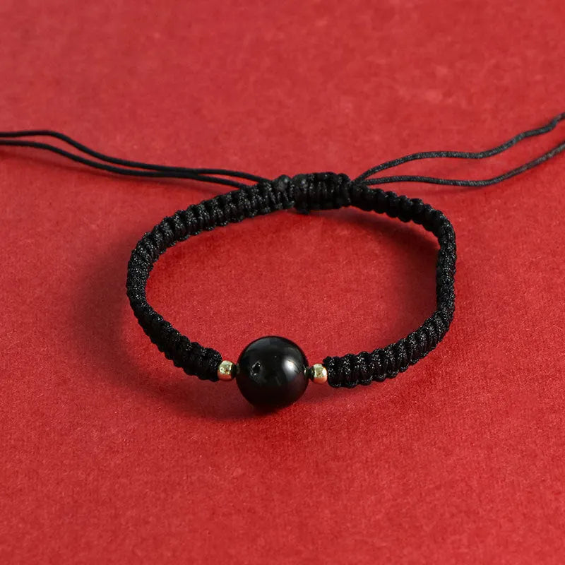 A woven red rope bracelet with a natural strawberry quartz bead and an alloy clasp.