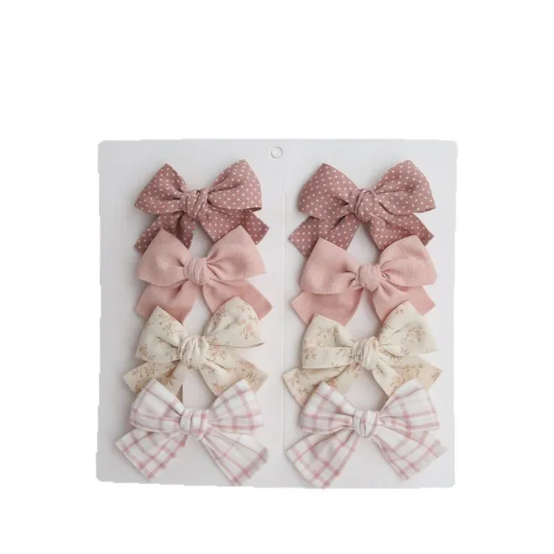 Set of children's cloth hairclips with a dovetail bow design in various colours including beige and blue flowers.