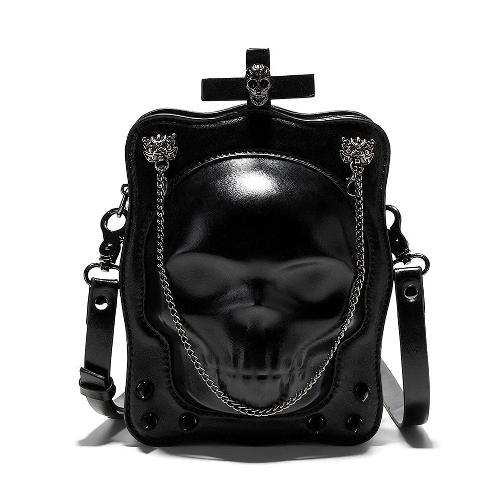 Black square crossbody bag with embossed skull design and metal chain strap against dark background