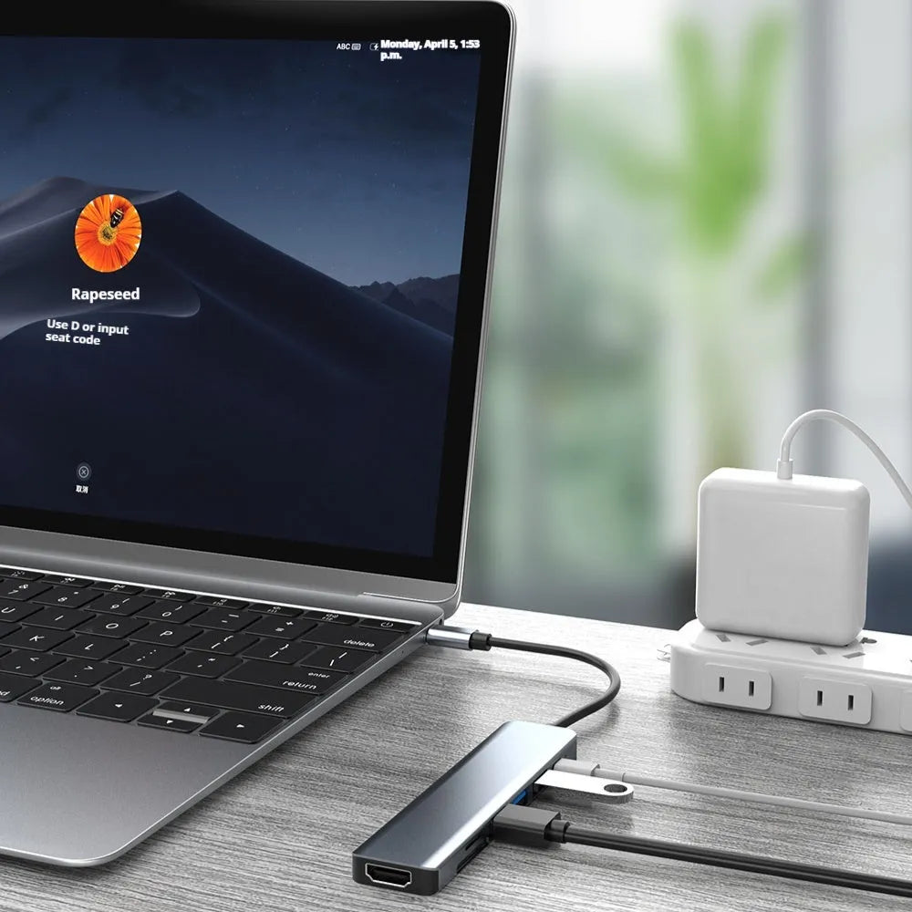 Silver 7-in-1 USB C hub docking station with HDMI, USB ports, and card readers on a desk.