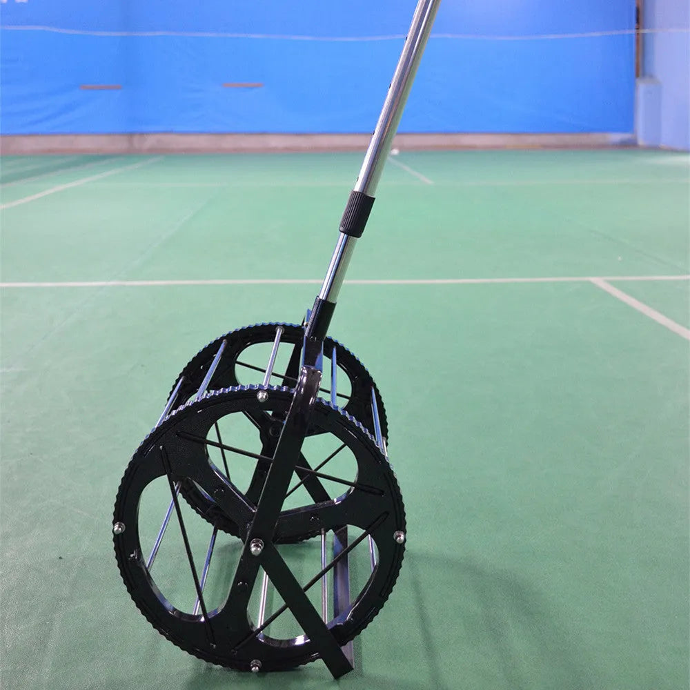 Black tennis ball picker basket made from nylon and metal, holding multiple tennis balls on a court