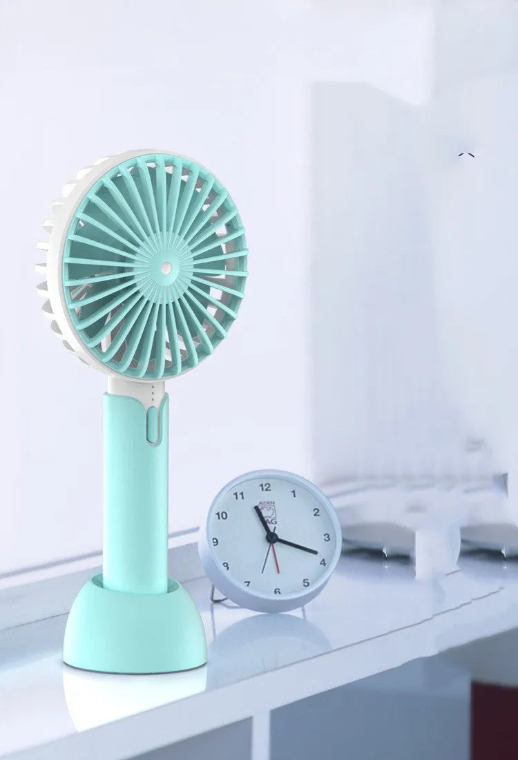 Blue handheld portable mini fan with USB cable, three-speed buttons, and shaking head design on desktop