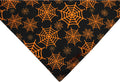 Black and orange reversible Halloween dog bandana with pumpkin and spider web patterns, showing adjustable neck strap