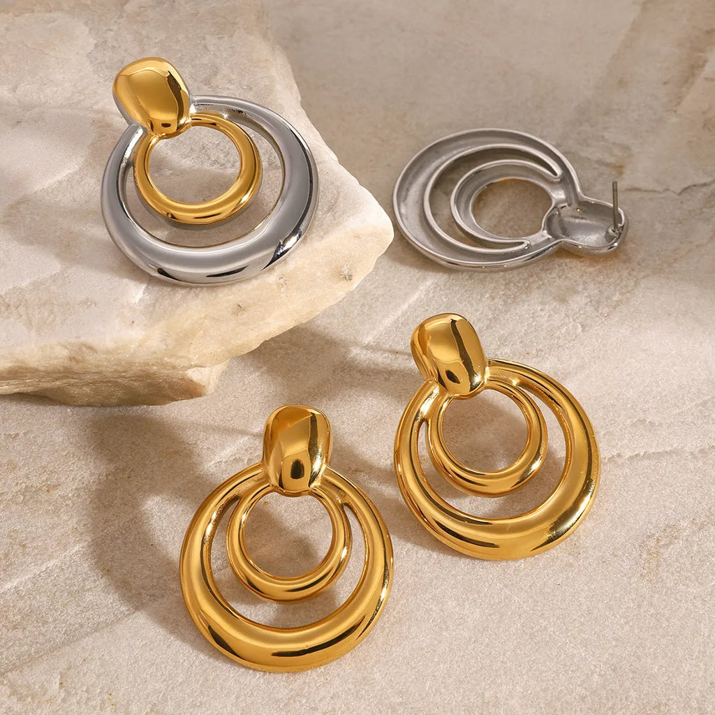 A pair of round, geometric double-layer hollow stud earrings with an 18K gold plated finish.