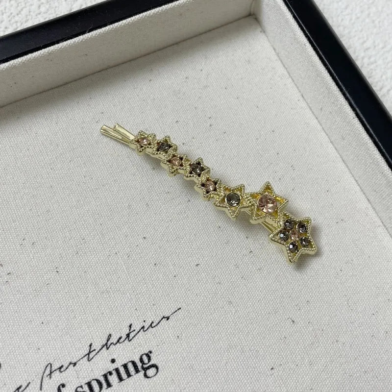 Gold-coloured alloy hair barrette with a rhinestone five-pointed star, shown as a side clip.
