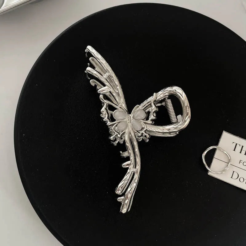 Silver metal hair claw barrette showing one of 45 designs, such as a bow or rose, on a white background.
