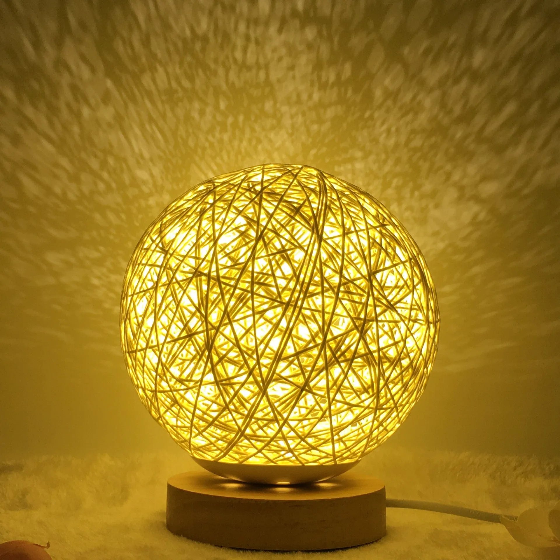 Rattan ball table lamp with woven shade and warm LED lighting on wooden surface