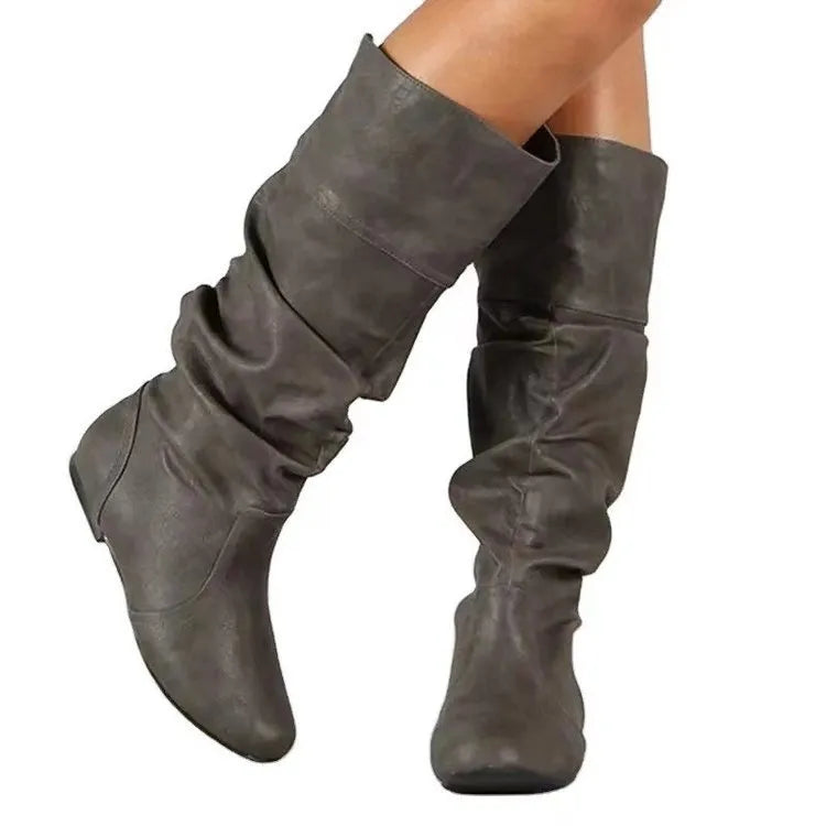 Women's flat black slip-on boots with a round toe and high cylinder shaft on a neutral background.