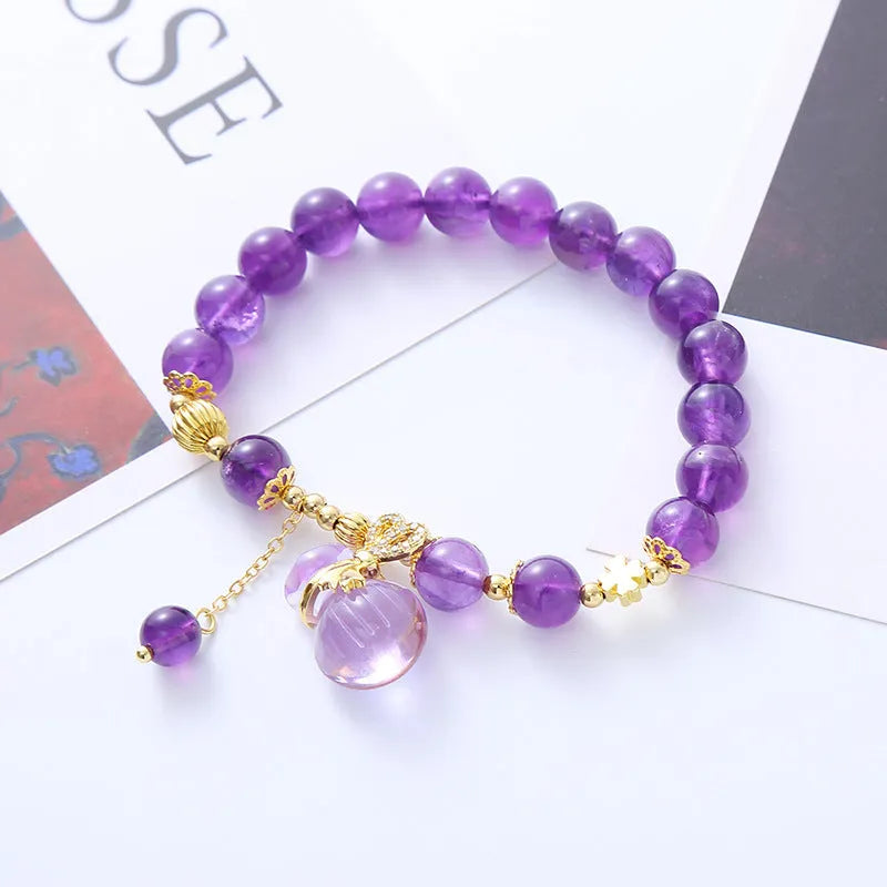 Purple amethyst crystal bracelet with money bag charm and peace buckle on woman's wrist