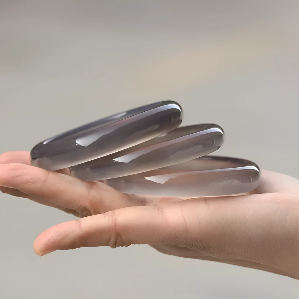 Dark gray iced chalcedony agate bracelet with circle, ring and line elements on neutral background