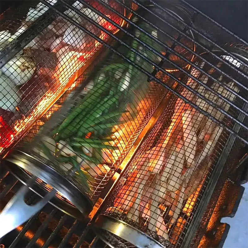 Round stainless steel rolling barbecue grilling basket with mesh sides and a hook, shown with assorted vegetables inside.