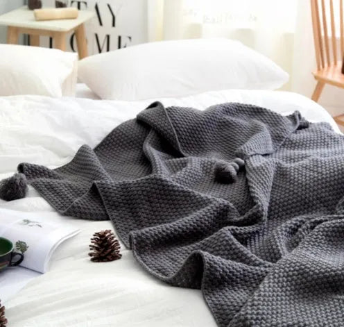 Nordic fringed knit ball acrylic blanket in beige, 130x170cm, on a sofa