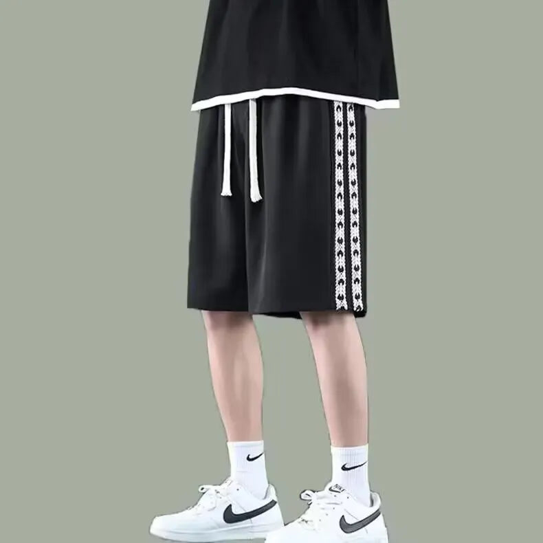 Man wearing loose-fit black track pants, showcasing the baggy sports style and elastic waist.