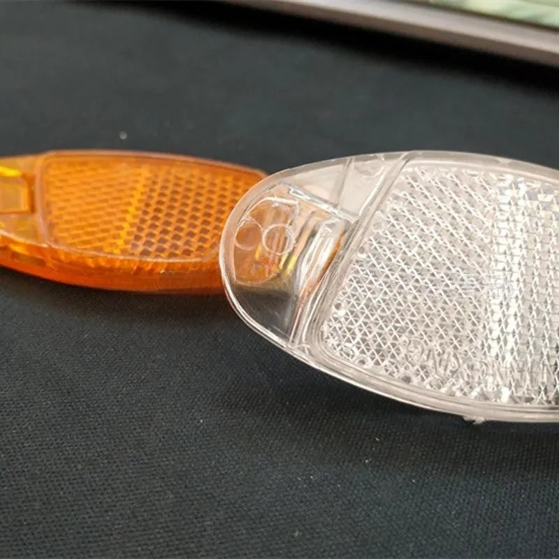White and yellow plastic bicycle spoke reflectors showing 7.2cm length measurement