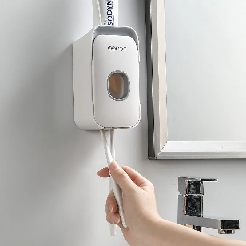 Blue automatic wall-mounted toothpaste dispenser with a sensor for touchless operation on a bathroom wall.