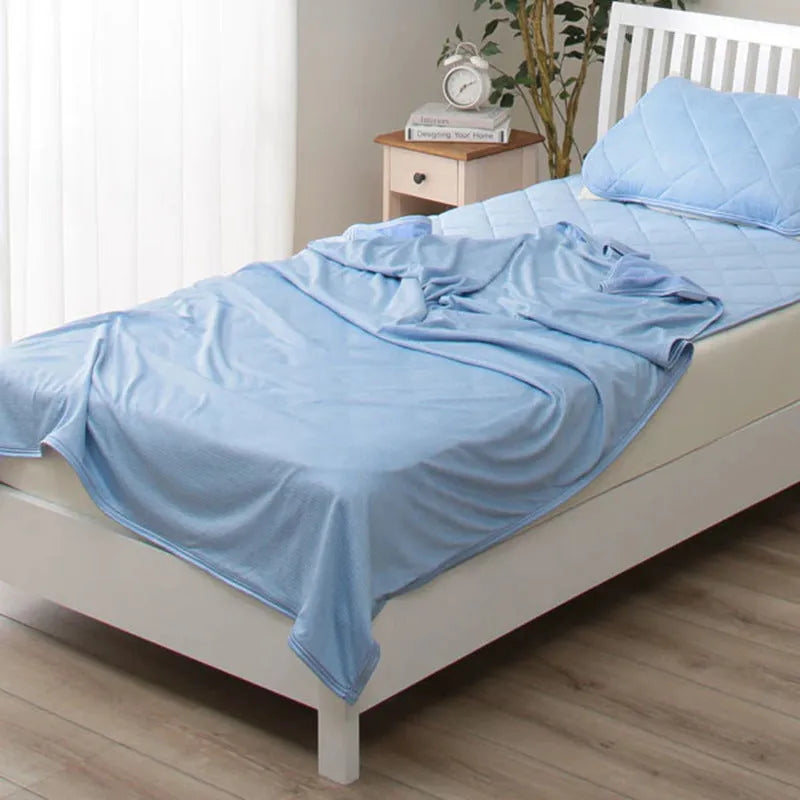 Cooling blanket in blue, grey, and pink colours on a bed, showing the polyester weave and Q-Max cooling fiber technology