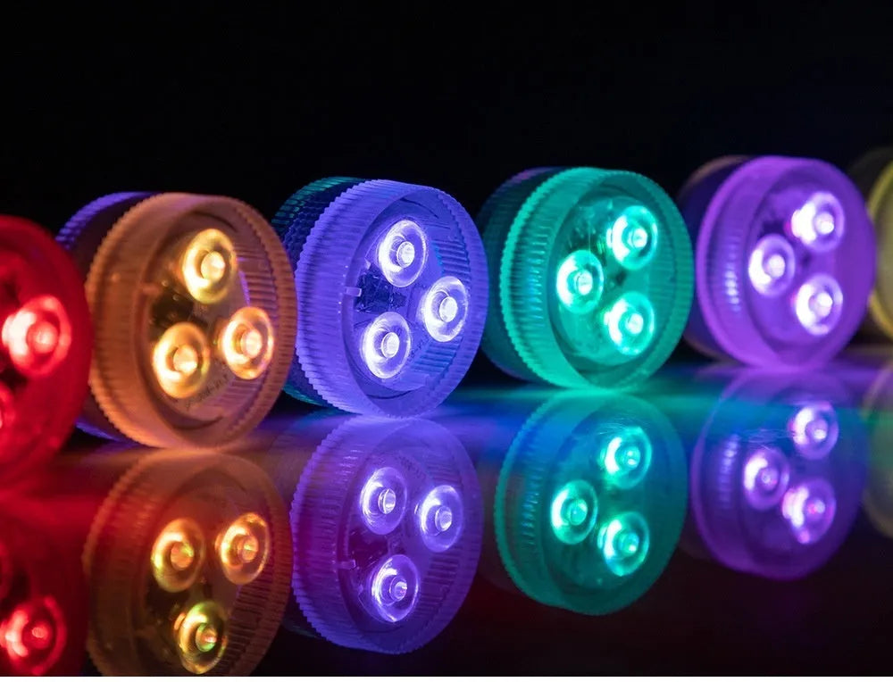 Small round remote control LED diving light for aquarium next to its multi-button remote on a table.