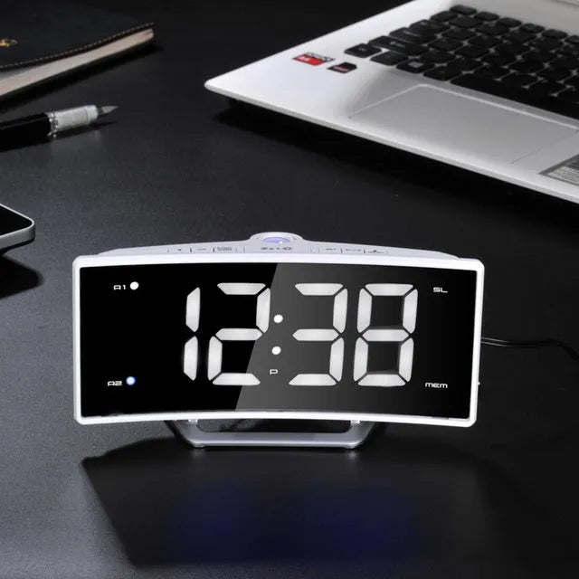 Curved screen LED projection alarm clock showing time on display with USB port and FM radio controls