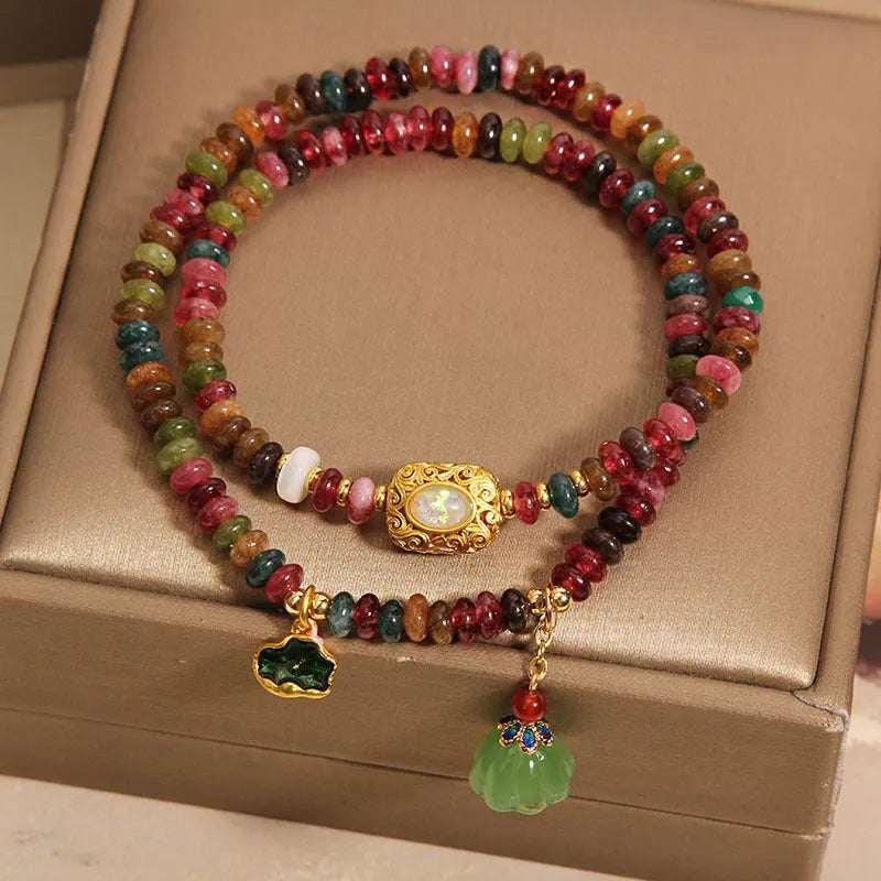 Rainbow tourmaline abacus beads double ring bracelet with lotus seedpod and flower shapes, on white background