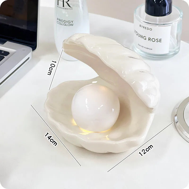 White and pink porcelain shell-shaped tray with integrated yellow LED night light on a wooden table.