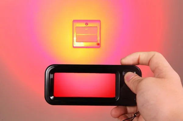 Small red handheld reverse camera detector with scanner for finding hidden surveillance lenses.
