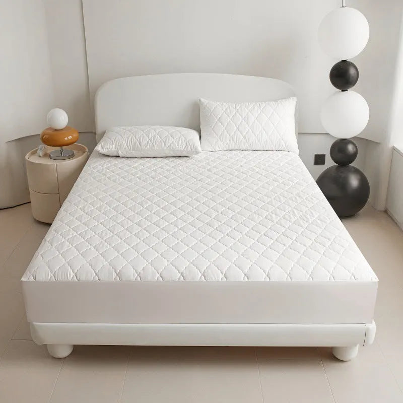 Diamond quilted black waterproof mattress protector fitted sheet and pillowcases set on a bed