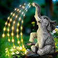 Outdoor resin elephant garden statue with integrated light strip on grass.