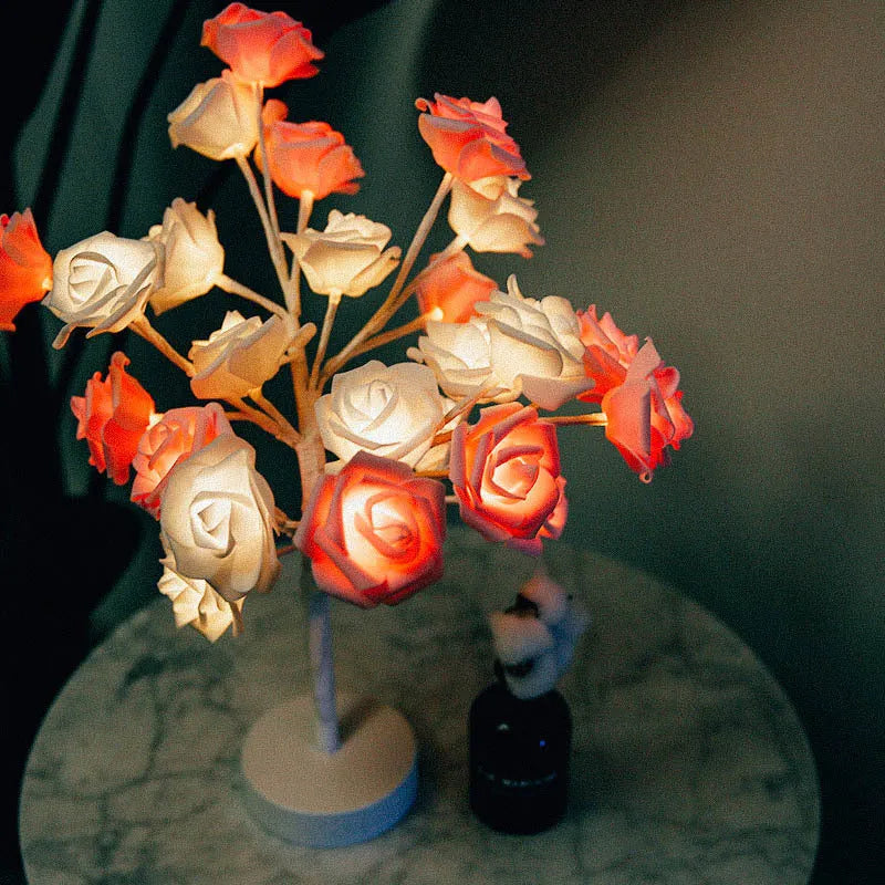 White and red rose flower LED table lamp with bonsai tree garland on a wooden table.