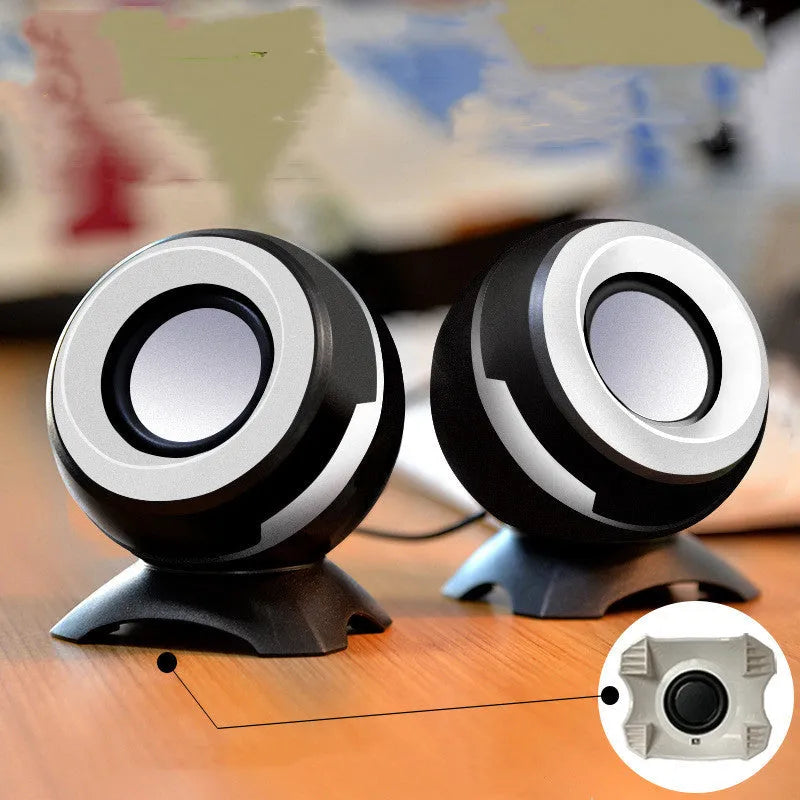 Black and gold USB-powered desktop computer speakers beside laptop showing compact 10cm dimensions