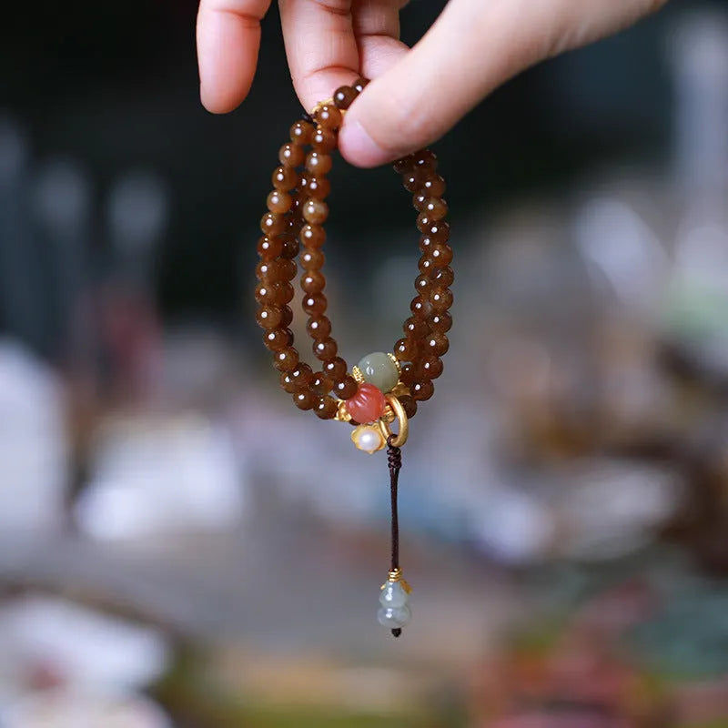 Brown Hetian Jade three-ring bracelet with butterfly and gourd charms on a wrist.