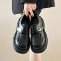 Retro platform loafers for women in solid colour black with square heel and round toe on a neutral background