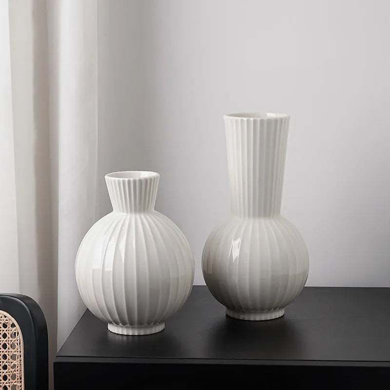 White ceramic ball vase with blue stripes, a silk blue orchid, on a wooden table.
