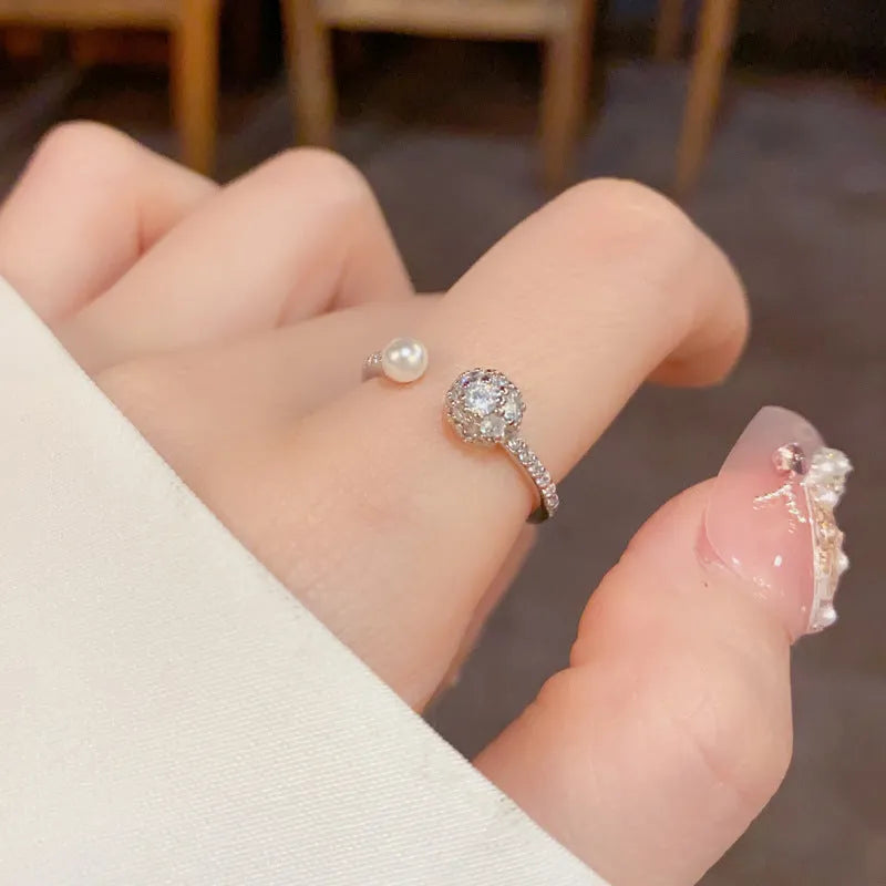 Gold or silver plated open-end pearl ring with round zircon stone on copper base.