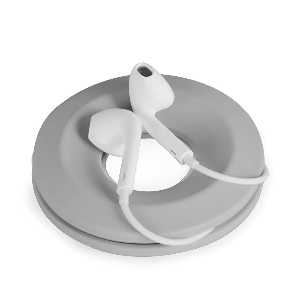 Light grey silicone donut cord reel with suction cup base and magnet for organising phone and earphone cables.