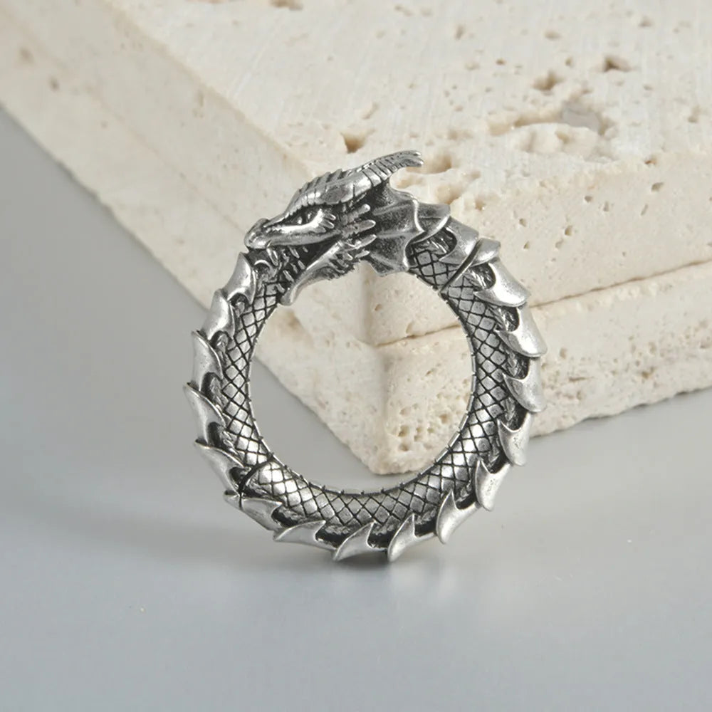 Pair of large antique silver dragon-shaped geometric ear cuffs with hollow-out detail on a plain background.