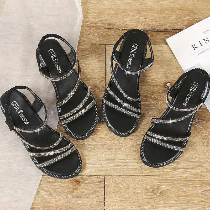 Women's silver flat sandals with rhinestone embellishment and an elastic strap on a rubber sole.