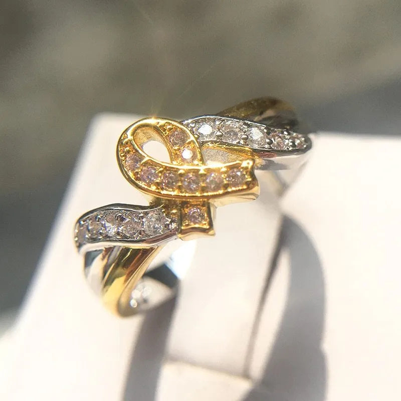 18k yellow gold plated ribbon engagement ring with pink diamond inlay on white background