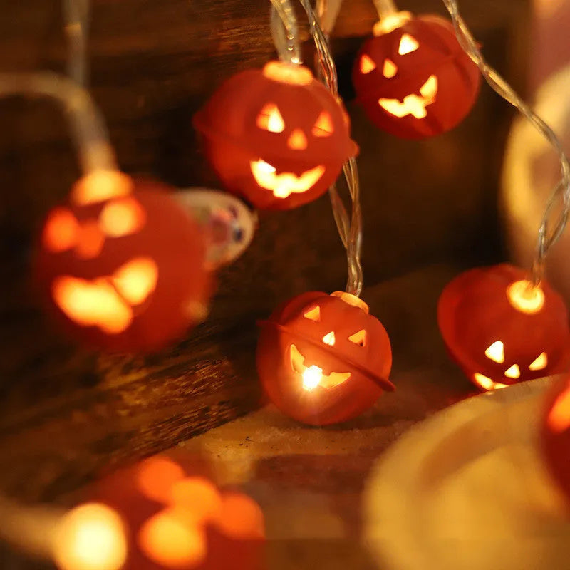 LED Halloween string lights with warm white glow and iron pumpkin pendants on a dark background