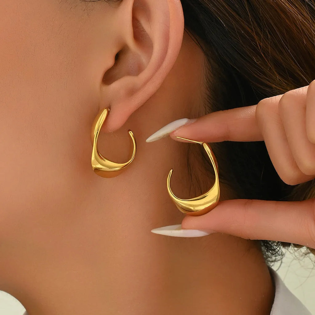 Geometric gold earrings with ring shape on stainless steel post-back closure against white background