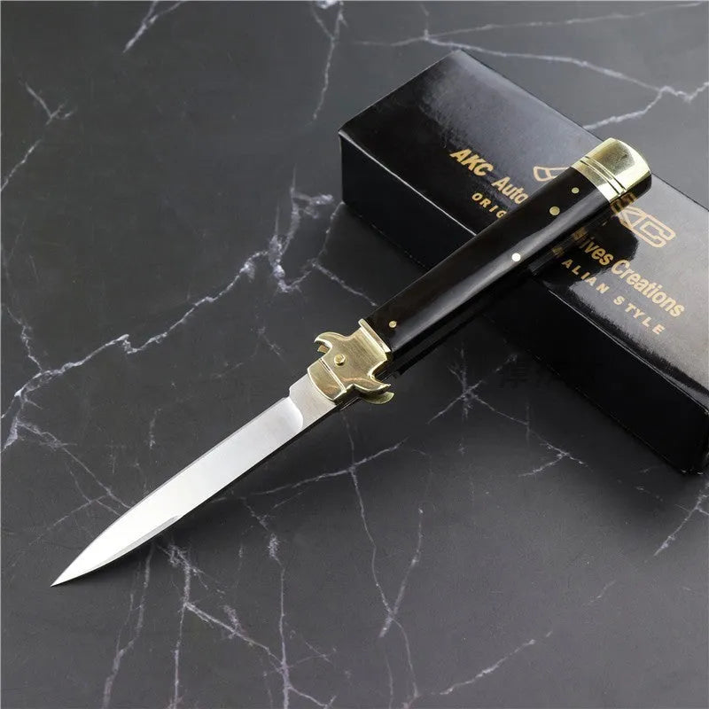 Damascus folding knife with 9.8cm blade and snake wood handle on outdoor wood surface