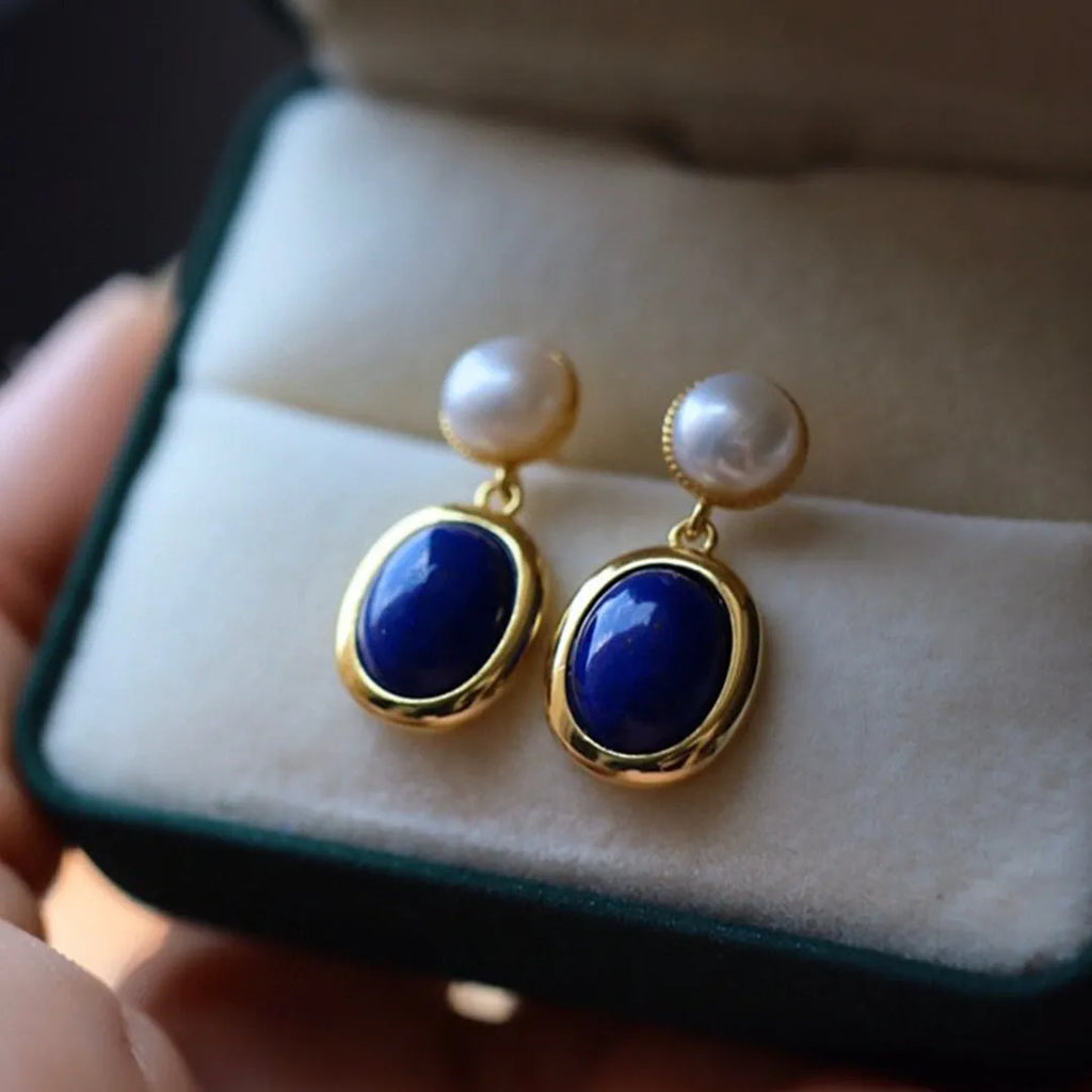 A pair of simple drop earrings featuring a blue lapis lazuli pearl set in patterned sterling silver.