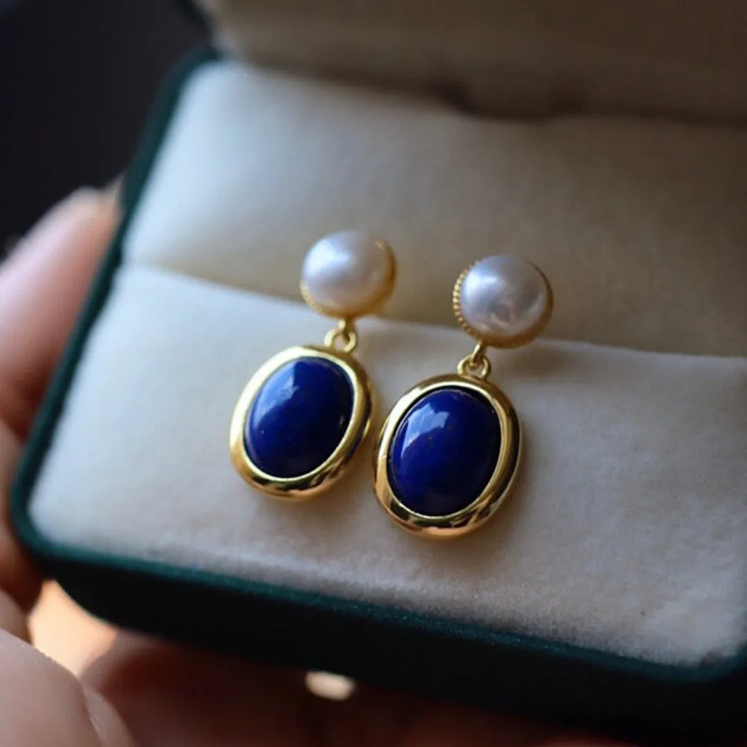 A pair of simple drop earrings featuring a blue lapis lazuli pearl set in patterned sterling silver.