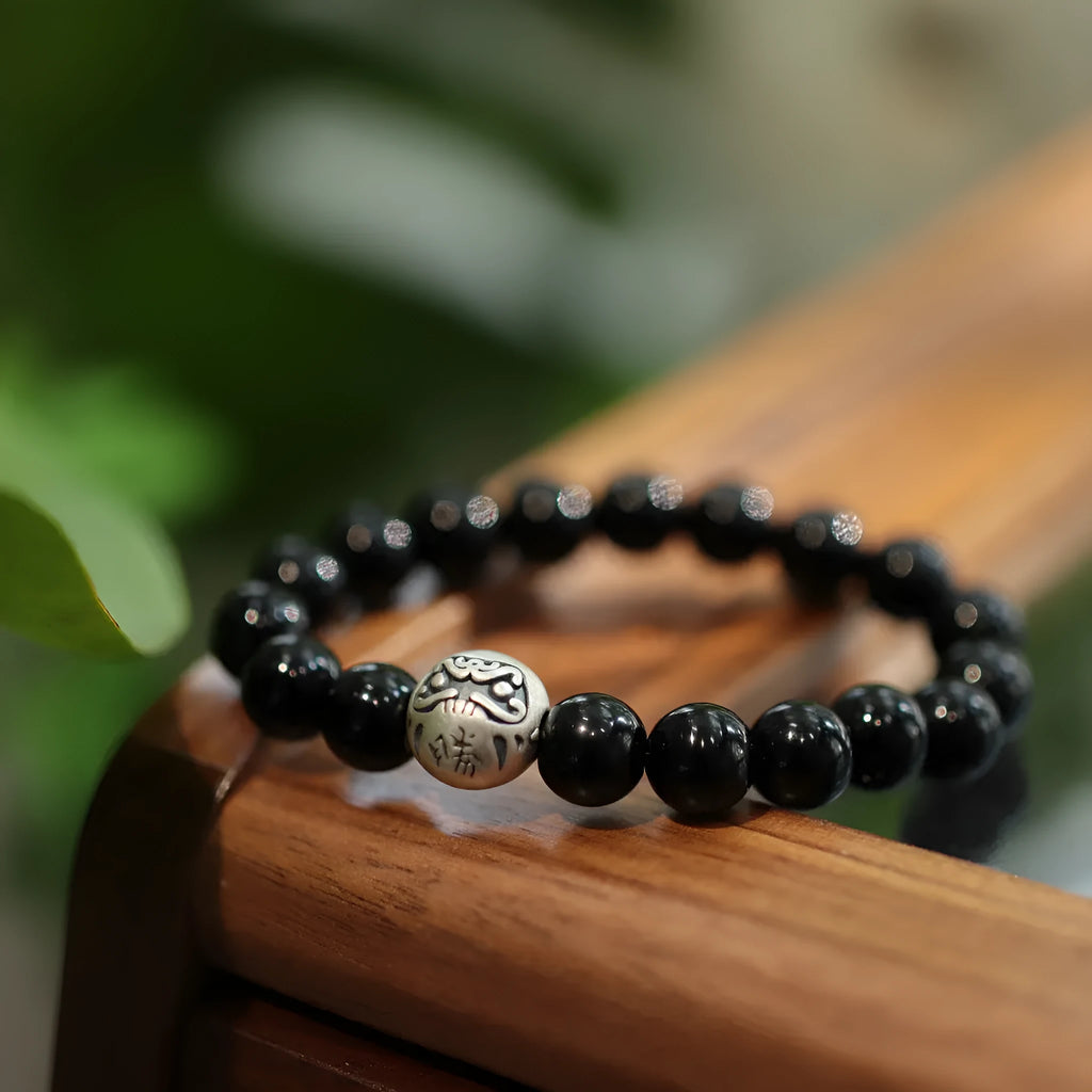 Close-up of a black bracelet with 10mm agate beads and sterling silver details on a wrist.