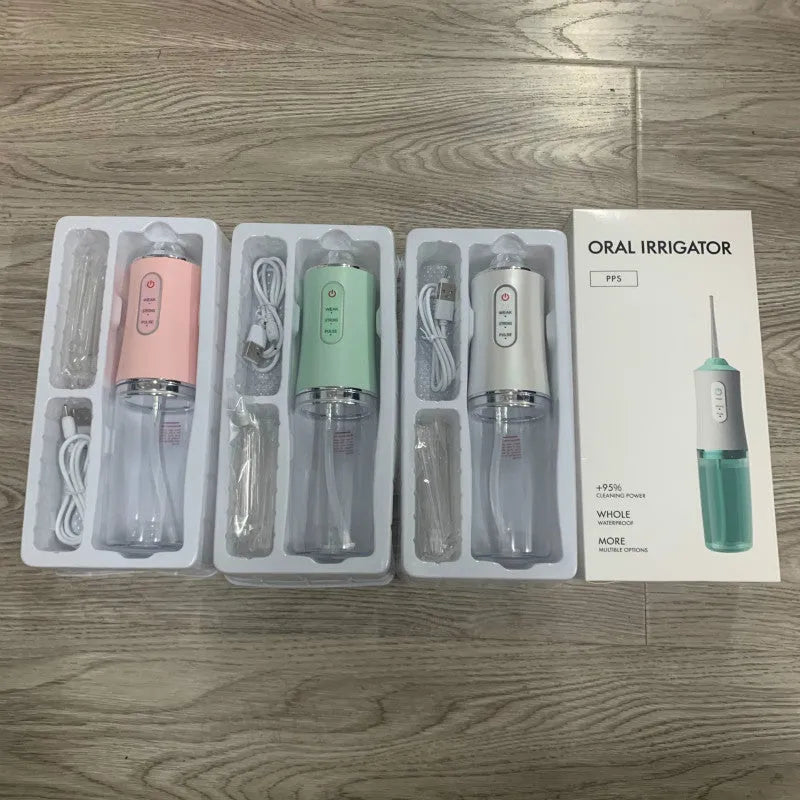 White portable oral irrigator with four nozzles and USB charging cable on a bathroom surface