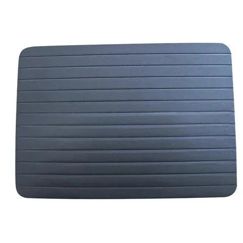 Black aluminium fast defrosting tray with silica gel feet on a kitchen countertop.