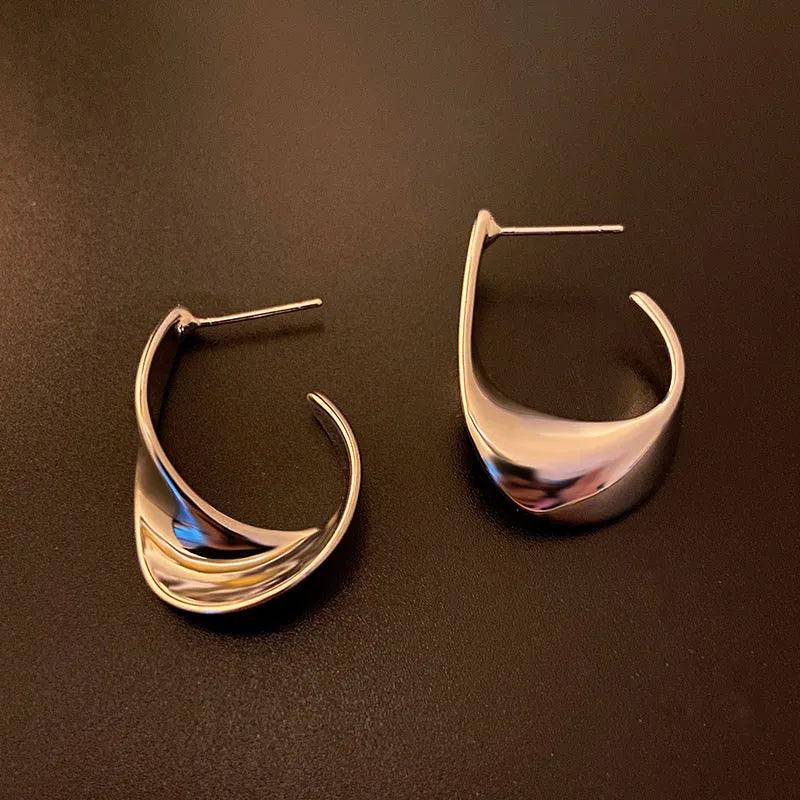 A pair of twisted geometric round metal earrings with a gold electroplated finish on a white background.