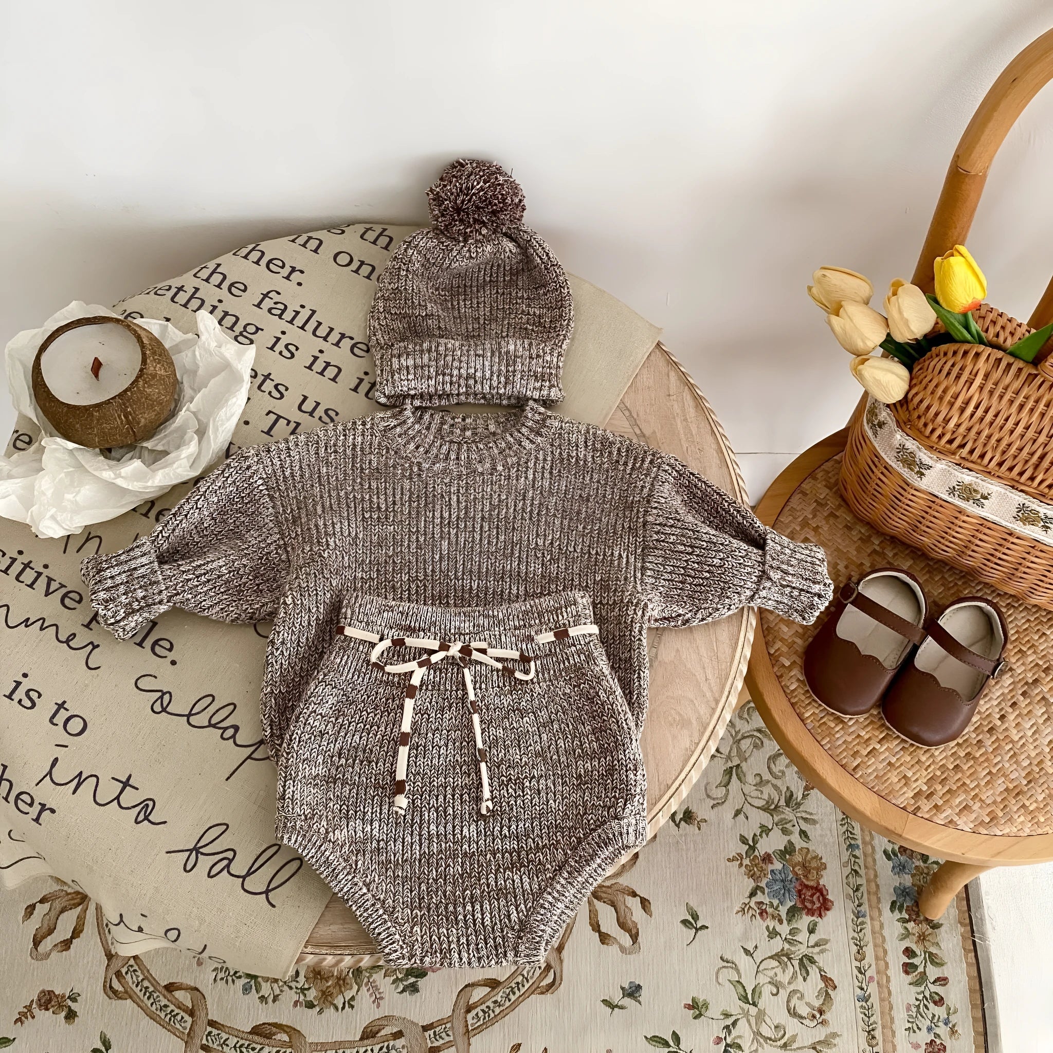 Dark brown knitted three-piece set for infant girl with fur ball hat, blouse, and shorts.