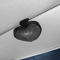 A black PU leather magnetic storage clip with a diamond pattern on a car sun visor, holding a pair of sunglasses.