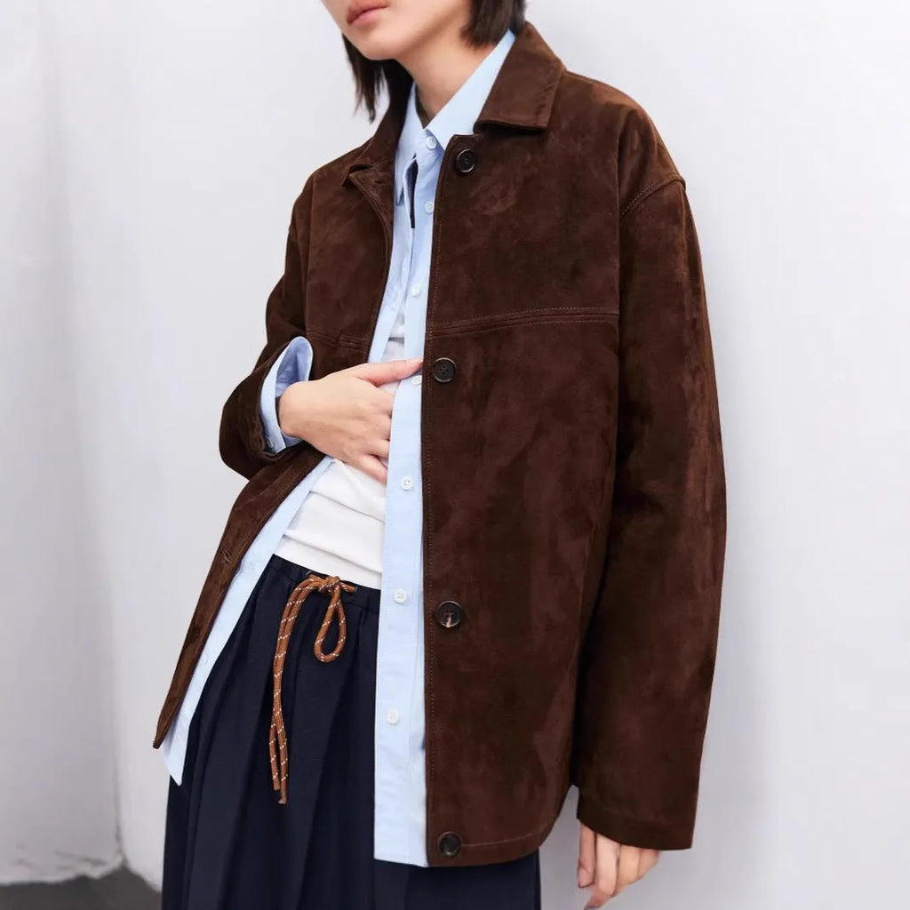 Yellow brown mid-length cashmere coat with a Peter Pan collar and leather stitching on a hanger.